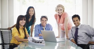 Smiling colleagues at table with laptop